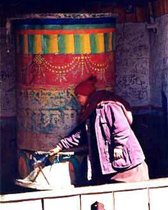 Tibetan Buddhist Nun in Himalayas of Nepal turning a large prayer