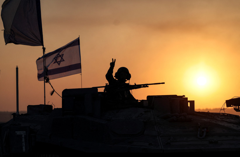 An Israeli soldier looks out from a tank at sunset as an artillery unit gathers near Israel's border with the Gaza Strip, in southern Israel, October 12, 2023.  (photo credit: REUTERS/Ronen Zvulun)