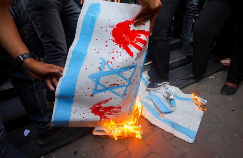  Demonstrators burn banners depicting the Israeli flag during a protest against Israel and the USA in support of Palestinians for those killed in a blast at Al-Ahli hospital in Gaza that Israeli and Palestinian officials blamed on each other, amid the ongoing conflict between Israel and Hamas, in Ca (photo credit: REUTERS/AMR ABDALLAH DALSH)